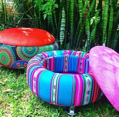 three colorful cushions sitting in the grass next to plants