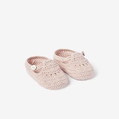 a pair of pink crocheted slippers with buttons on the toes and bottom