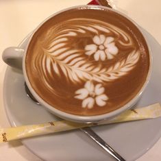 a cappuccino on a saucer next to a spoon and measuring tape