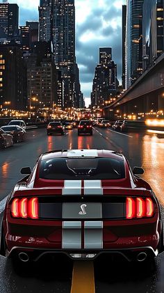 a red sports car is driving down the street in front of tall buildings and skyscrapers