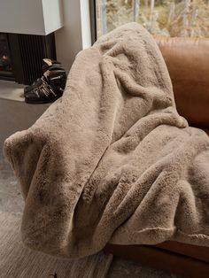 a brown couch covered in a blanket next to a fire place