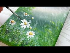 someone is painting daisies in the grass