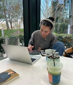 a woman sitting at a table working on her laptop