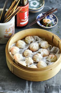 some dumplings are in a wooden bowl with chopsticks and sauce on the side