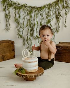 a baby sitting on the floor in front of a cake