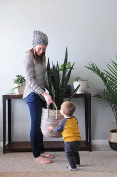 a woman holding a basket next to a small boy in front of potted plants