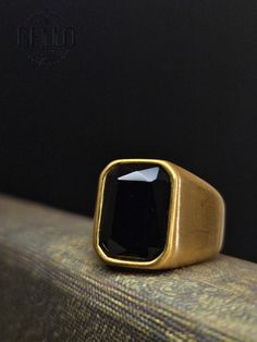 Stainless Steel Rings: Elevate your style with our Bold Men's Gold Stainless Steel Signet Ring featuring a striking black stone. This ring is designed to make a statement, adding a touch of sophistication and modernity to your look. Perfect for any occasion, it complements both casual and formal attire. Material: Gold Finish Stainless Steel Stone: Black Cubic Zirconia (CZ) Design: Bold and modern signet ring style Features: Hypoallergenic, suitable for sensitive skin Perfect For: Daily wear, spe Classic Black Crystal Promise Ring, Classic Black Crystal Ring For Gift, Wedding Black Polished Finish Signet Ring, Vintage Black Adjustable Signet Ring, Vintage Adjustable Black Signet Ring, Black Stainless Steel Open Ring, Black Stainless Steel Open Ring Jewelry, Black Open Ring Crystal Wedding Ring, Black Crystal Ring For Gift