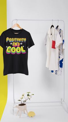 a t - shirt hanging on a clothes rack next to a small potted plant