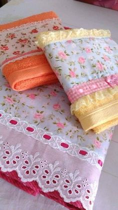 three folded towels on top of each other with pink and yellow laces around them