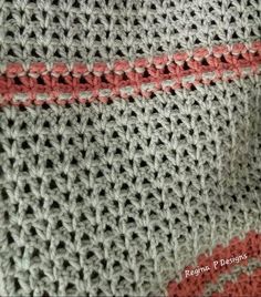 a close up view of a knitted blanket with red and gray stripes on it