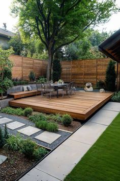 a wooden deck in the middle of a yard with grass and plants around it, surrounded by trees