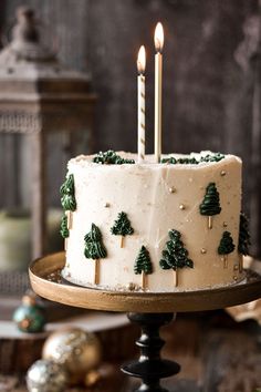 a cake with white frosting and green trees on it is sitting on a table