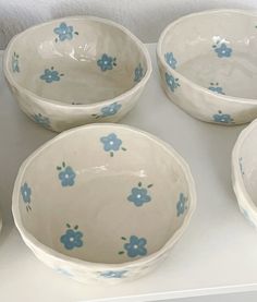 four white bowls with blue flowers on them