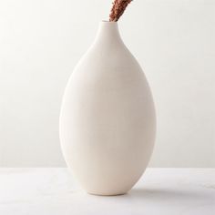 Rounded vase is crafted of clay for an organic sensibility. Warm white vessel is glazed by hand to highlight the striking tonal variations and texture of the finish. A distinctive accent on its own or for showcasing dried botanicals. CB2 exclusive.  -Handmade -Earthenware with white glaze -Pieces will vary in glaze coloring and tone -Decorative use only; not watertight -Wipe with a soft cloth -Botanicals not included -Made in Portugal Haute Warm White Ceramic Vase Tall Tall White Vase, Lotus Flower Candle Holder, Spruce Essential Oil, Wood Pillar Candle Holders, Black Taper Candles, Black And White Vase, Rectangular Vase, Vase Tall, White Pillar Candles