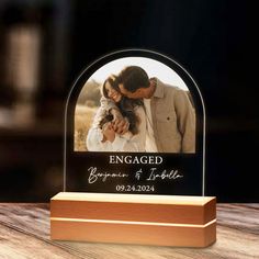 an engraved glass photo frame on a wooden base with the words engaged written in it