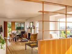 a living room filled with furniture and lots of windows next to a wooden floor covered in plants