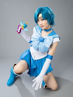 a woman with blue hair and white gloves holding a toy in one hand while sitting on the ground