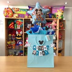 a blue bag with mickey mouse on it sitting on a table in front of toys