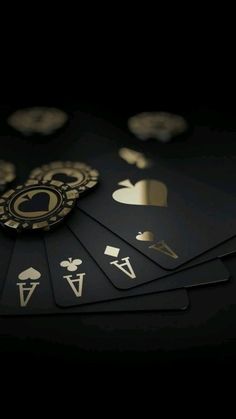 several playing cards with gold and black designs on the sides, all in different shapes and sizes