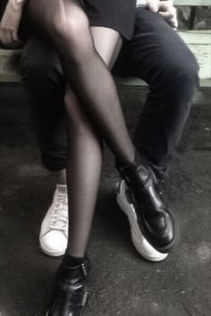 two people sitting on a bench with their legs crossed and one person wearing white shoes