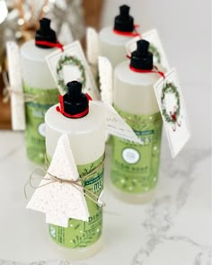 six green bottles with white labels on them sitting on a table next to a christmas tree