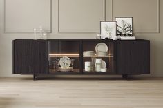 a sideboard with plates and other items on it in a room that has wood floors