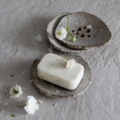 two pieces of soap sitting on top of each other next to white flowers and petals