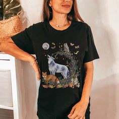 a woman standing in front of a wall wearing a t - shirt with an image of a wolf and two cats on it