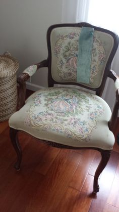 an old chair is upholstered with fabric on the back and sides, along with a basket