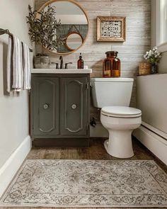 a white toilet sitting next to a sink in a bathroom under a round mirror on the wall