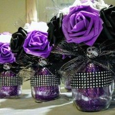 purple and black roses are in glass jars