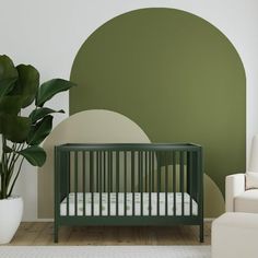 a baby's crib in front of a green and white wall with a potted plant