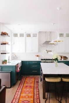 a kitchen with green cabinets, white counters and an area rug on the hardwood floor