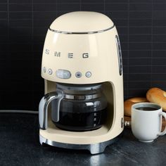 a coffee maker sitting on top of a counter next to a cup and donuts