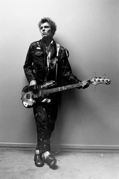 black and white photograph of a man holding an electric guitar in front of a wall