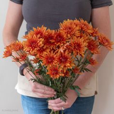 a woman holding a bouquet of orange flowers