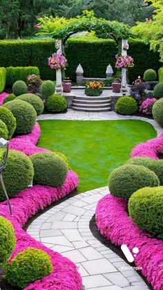 an outdoor garden with pink flowers and green grass in the center, surrounded by stone walkways