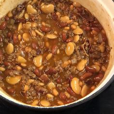 a pot filled with chili and beans on top of a stove next to some bread