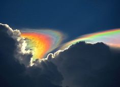 a rainbow appears in the clouds as it is partially hidden by its bright, colorful tail