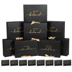 six black boxes with gold foil lettering and ribbon tied around the top, each box has a different name on it