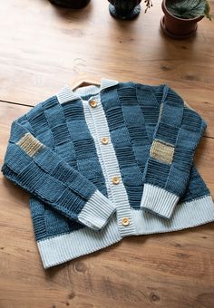 a blue and white sweater sitting on top of a wooden floor next to a potted plant