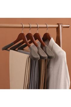 clothes hanging on wooden hangers in front of an orange wall