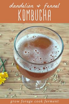 a glass filled with liquid next to flowers on top of a wooden table and text that reads, dandelion & fennel kombucha