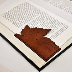 an open book with a leaf cut out of it sitting on top of a table