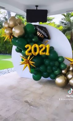 the balloon arch is decorated with gold and green balloons