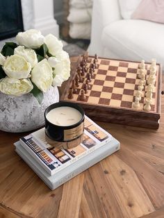 a vase with white flowers sitting on top of a table next to a chess board