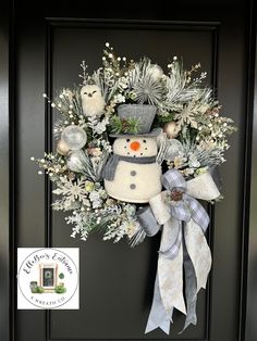 a snowman wreath on the front door is decorated with silver and white flowers, pine cones and evergreens