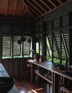 a room with wooden floors and windows that have shutters on the sides, along with a ladder leading up to it