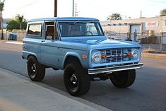 an old blue truck is parked on the street