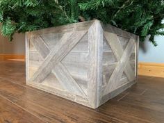 a wooden box sitting on top of a hard wood floor next to a green tree